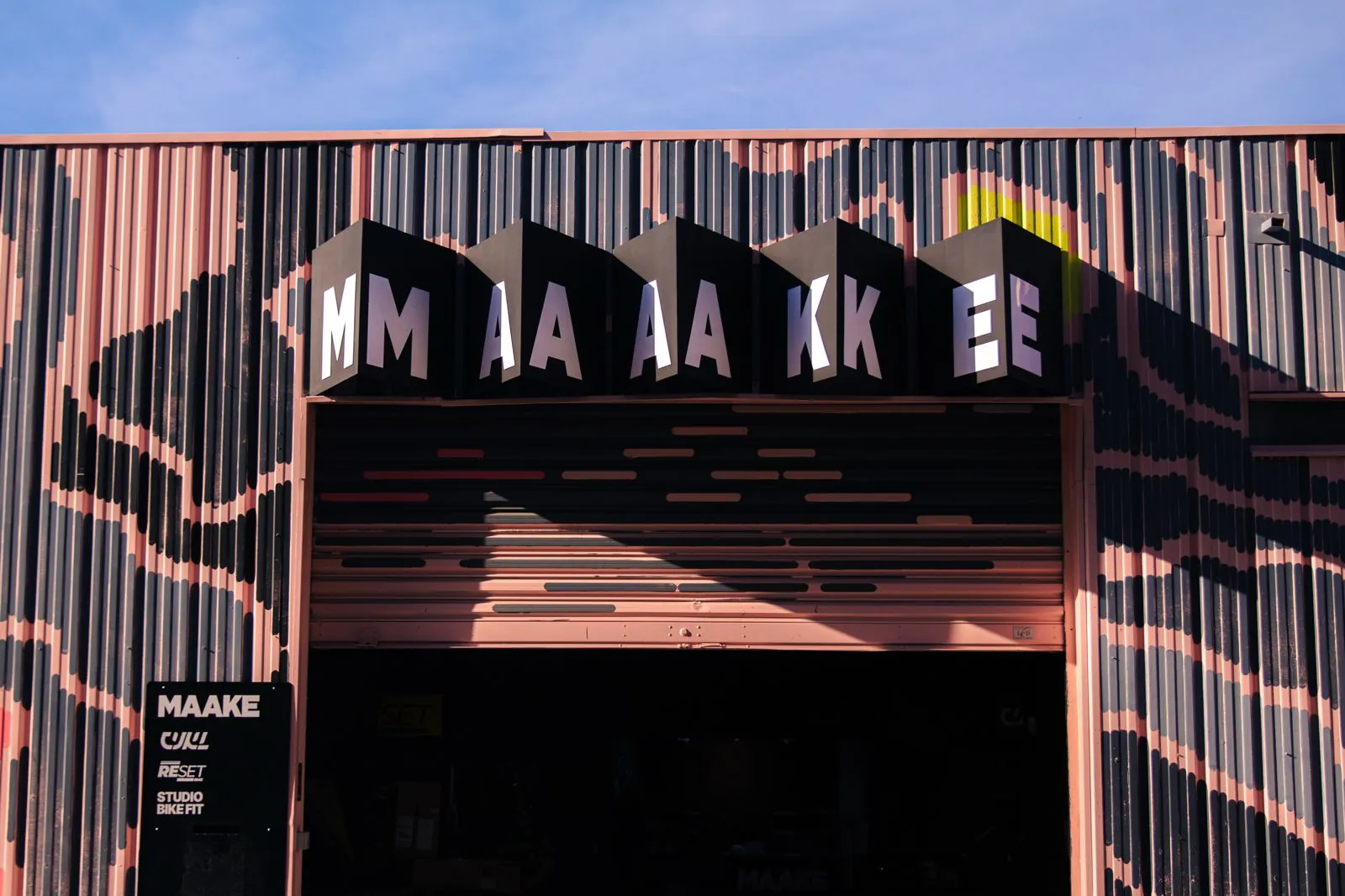 The front of the MAAKE hub in Montpellier, with the MAAKE sign above the shutter and the CYKL, Reset BMX and Studio Bike Fit plaque by the door.